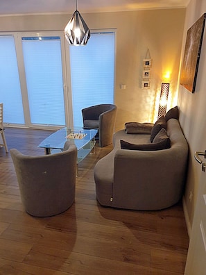 A modern living room with a glass coffee table, two armchairs, a sofa, and a hanging light fixture. - 1st floor, modern amenities, central location, about 200 m from the sandy beach (Baltic Sea) (Juliusruh)