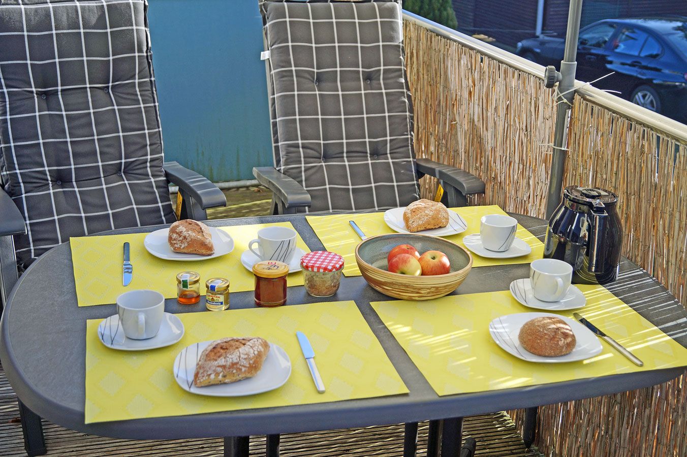Una mesa preparada para el desayuno, con platos de comida, tazas y una cafetera.
