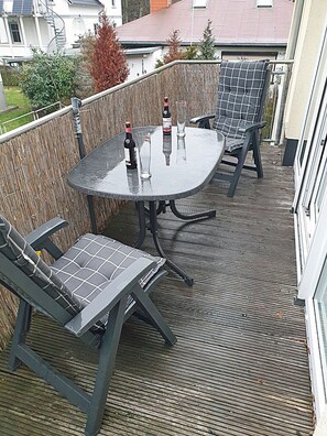 An outdoor patio with a round table and four chairs, a bottle of wine, and a glass on the table. - 1st floor, modern amenities, central location, about 200 m from the sandy beach (Baltic Sea) (Juliusruh)