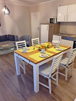 A dining area with a wooden table, white chairs, and a glass coffee table. - 1st floor, modern amenities, central location, about 200 m from the sandy beach (Baltic Sea) (Juliusruh)