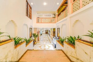 Eine Hotelhalle mit einem zentralen Korridor, dekorativen Geländern und Topfpflanzen.