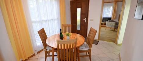 Uma área de refeições com uma mesa redonda de madeira, quatro cadeiras e uma garrafa de vinho.