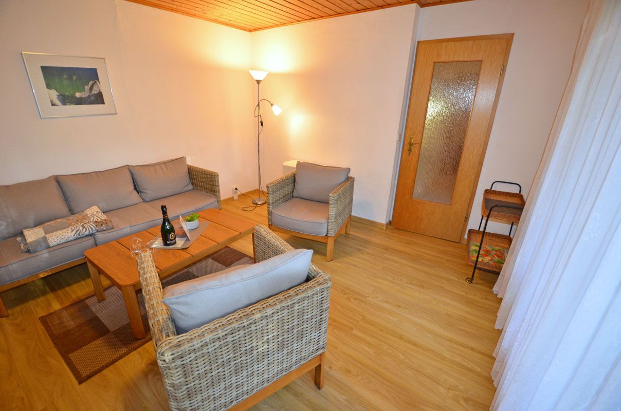 Ein möbliertes Wohnzimmer mit einer Couch, zwei Sesseln, einem Couchtisch und einer Stehlampe.