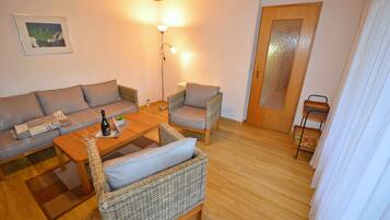 Ein möbliertes Wohnzimmer mit einer Couch, zwei Sesseln, einem Couchtisch und einer Stehlampe.