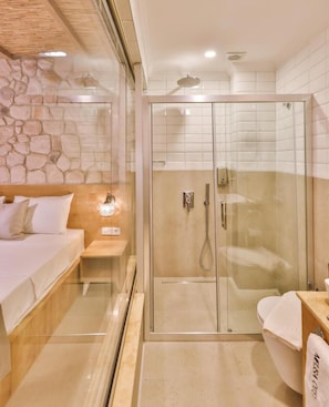 Ein modernes Badezimmer mit einer gläsernen Duschkabine, einem Nachttisch aus Holz und einem weißen Waschbecken.