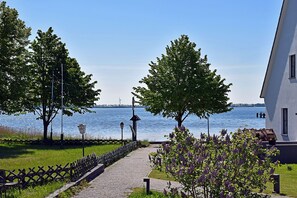 A pathway leading to a body of water with trees and a building on the right. - Modern vacation rental with ocean views, just 60 meters from the water, 2 bedrooms, Wi-Fi, pets allowed (Dranske)