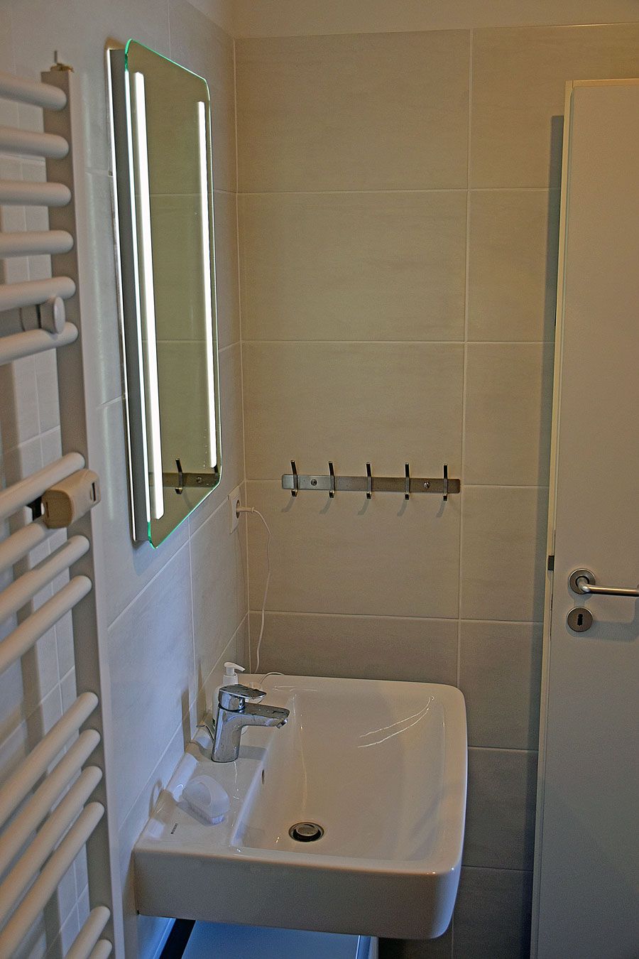 A bathroom with a white sink, a mirror, and a towel rack.