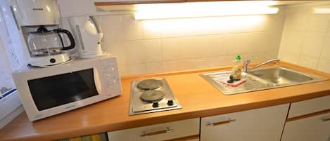 A compact kitchen with a microwave, coffee maker, and a sink.