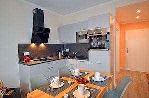 A compact kitchen with modern appliances, a dining area with a table set for four, and a separate dining space. - Vacation rental with a view of the water, 2 bedrooms, just 60 meters from the water, Wi-Fi (Dranske)