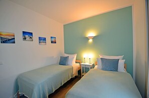 A room with two beds, a nightstand, and a wall-mounted lamp. - Vacation rental with a view of the water, 2 bedrooms, just 60 meters from the water, Wi-Fi (Dranske)