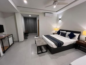 Ein modernes Hotelzimmer mit einem großen Bett, Nachttischlampen, einem Schreibtisch und einer kleinen Sitzecke.
