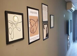Ein Flur mit gerahmten Bildern an der Wand, einer Tür und einem an der Wand befestigten Fernseher.