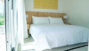 Un dormitorio con cabecera de madera, ropa de cama blanca y dos lámparas de noche.