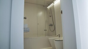 A modern bathroom with a glass shower enclosure, a toilet, and a sink. - Casa Grande Hotel & Beach Club (José Ignacio)