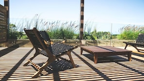 An outdoor seating area with wooden furniture and a view of tall grasses. - Casa Grande Hotel & Beach Club (José Ignacio)