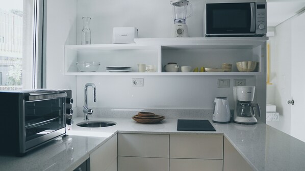 A modern kitchen with a toaster, sink, microwave, and coffee maker. - Casa Grande Hotel & Beach Club (José Ignacio)