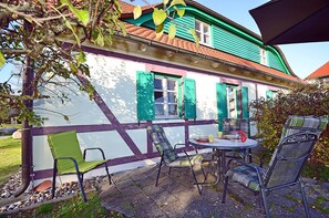 Ein Haus mit einer Terrasse, die Gartenmöbel und einen Tisch bietet.