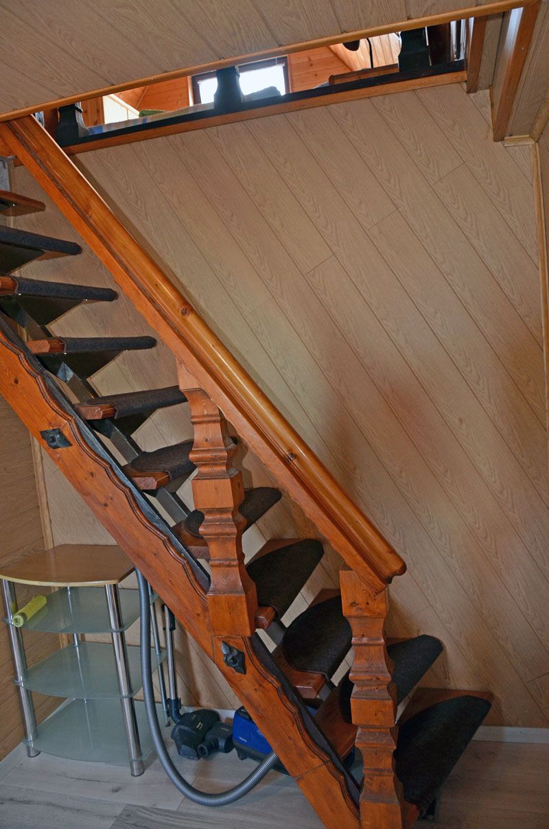 A wooden staircase with a handrail and a metal handrail on the side, leading to a lower level.