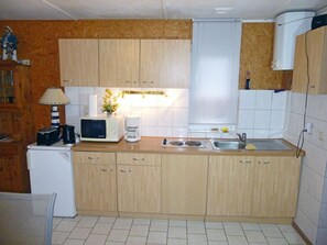 A compact kitchen with wooden cabinets, a microwave, a coffee maker, and a sink. - Bungalow right on the sandy beach of the Baltic Sea, sleeps up to 2 people, with 1 bedroom (Juliusruh)