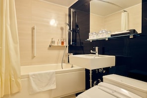 A modern bathroom with a bathtub, a sink, and a toilet. There is a towel hanging on the tub, and toiletries are placed on a shelf above the sink. - Hotel Kumamoto Terrace (Kumamoto)