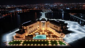 Um hotel grande e iluminado, com um pátio central e piscina, cercado por água.
