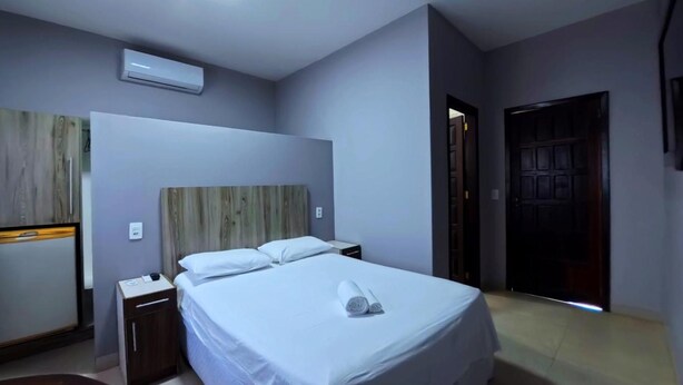A hotel room with a bed, bedside table, and an air conditioning unit. - Plaza Hotel (Sinop)
