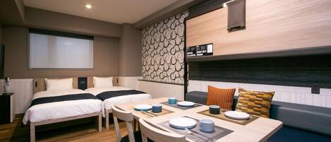 A compact room with two beds, a dining table, and a seating area.