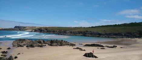 A beach with rocky outcrops and a clear sky.