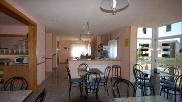 Cocina con isla central, comedor con sillas y vistas amplias por ventanas grandes.