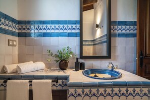 A bathroom with blue and white tiles, a sink, a mirror, and a potted plant. - Malaga Sierra de las Nieves by Real Spain Hotels (Casarabonela)