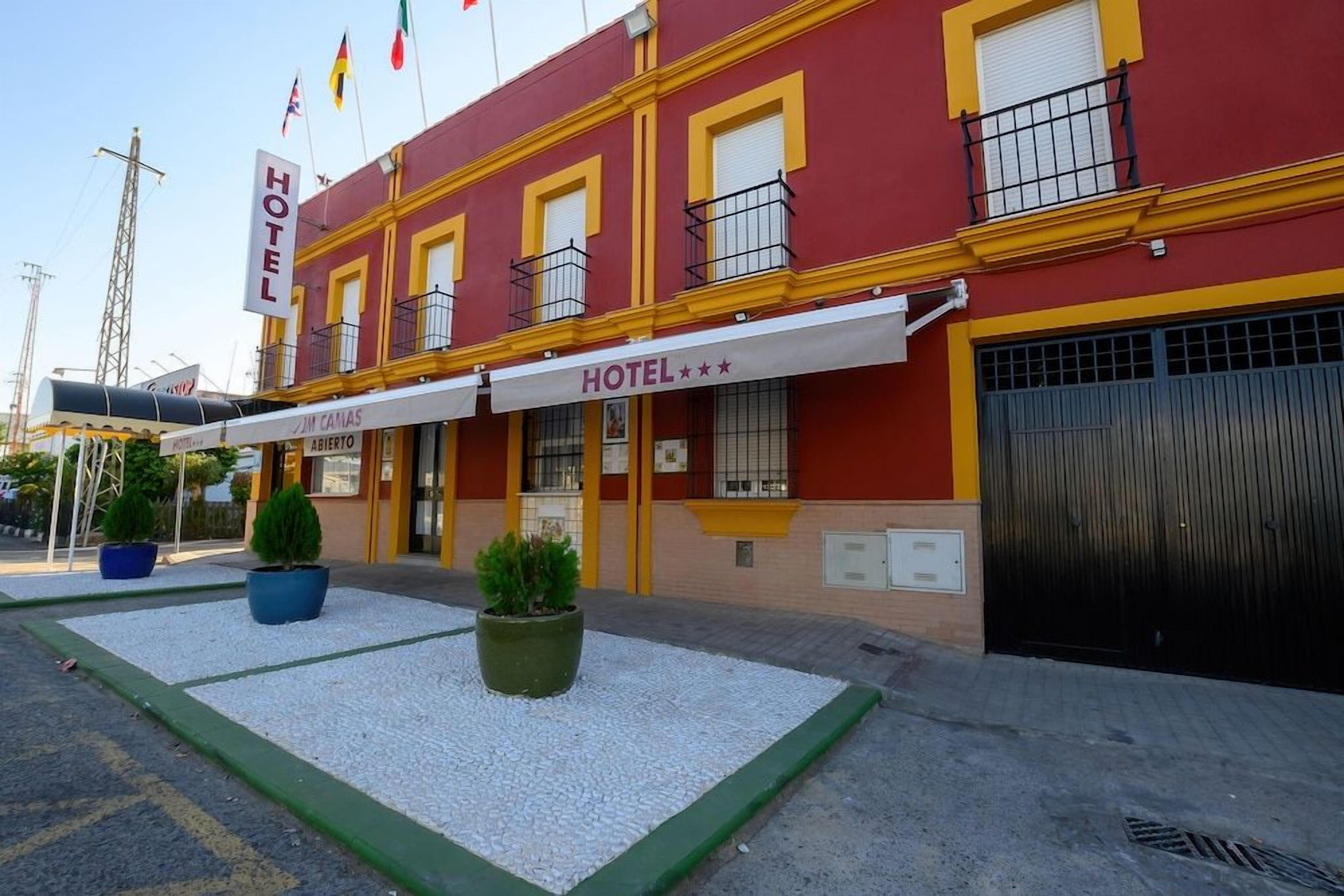 A hotel with a red facade, a signboard, and a covered entrance.
