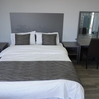 A hotel room with a bed, a desk, and a chair.