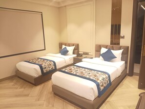 A hotel room with two beds, a large window, and a projector screen. - Hotel Cullinan By Qotel (New Delhi)