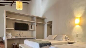 A room with two beds, a TV, and a bench.