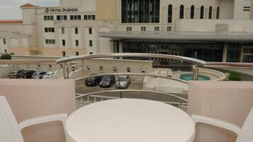 Eine Dachterrasse mit rundem Tisch und Stühlen, mit Blick auf einen Parkplatz und ein Hotelgebäude mit der Aufschrift 'HOTEL SPLENDID'.