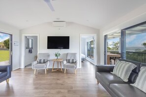 A spacious living room with a flat-screen TV, grey sofas, and a wooden coffee table. - Reflections Holiday Parks Lake Glenbawn (Glenbawn)