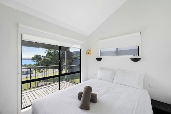 A hotel room with a large bed, a view of the outdoors, and a balcony.