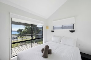Habitación de hotel con una cama grande, vistas al exterior y un balcón.