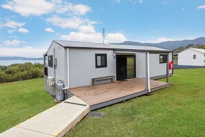 A single-story, modern building with a flat roof, a front porch, and a small deck.