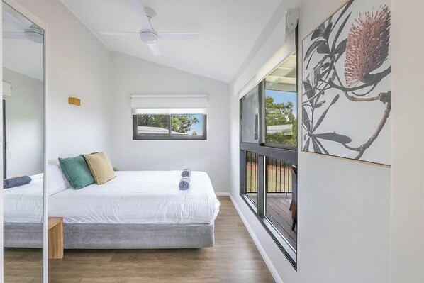 A bedroom with a bed, a window, and a ceiling fan.