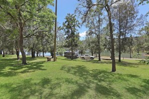 A campground with trees, grass, a lake, and RVs.
