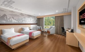 Een hotelkamer met twee bedden, een bureau, een stoel, een kleine tafel en een televisie.