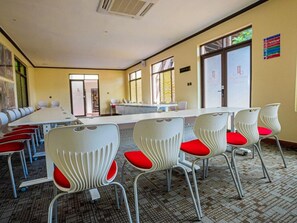 A conference room with a long table and white chairs with red cushions. - Light Villas (Nairobi)