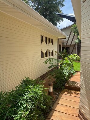 A narrow pathway flanked by a yellow building with a window with a unique geometric design. - Light Villas (Nairobi)