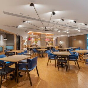 A restaurant with multiple tables and blue chairs, a bar area with bottles, and pendant lighting. - Guangzhou Zengcheng Tongpai Hotel (Guangzhou)