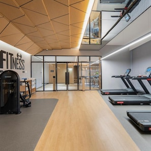 A gym with exercise equipment, a wall with 'FITNESS' signage, and a modern interior design. - Guangzhou Zengcheng Tongpai Hotel (Guangzhou)