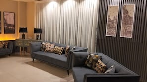 Una sala moderna con dos sofás, una mesita auxiliar y una lámpara.