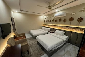 Habitación de hotel con dos camas, un escritorio, una silla, un televisor y decoración mural.