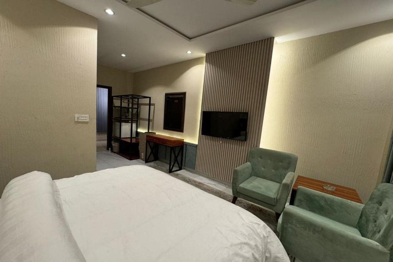 A hotel room with a bed, a desk, a chair, a television, and a wardrobe.