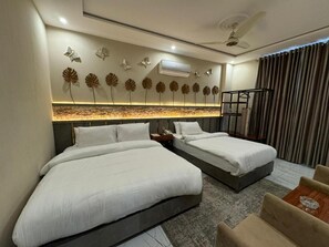 A hotel room with two beds, a seating area, a decorative wall with leaf patterns, and an air conditioning unit. - Shelton Boulevard Hotel (Lahore)